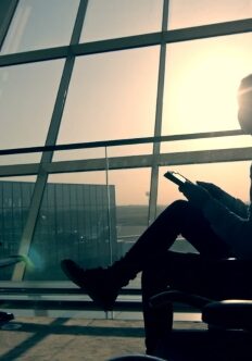 Businessman-using-tablet-computer-at-the-airport-silhouette-of-a-man-traveler-with-backpack